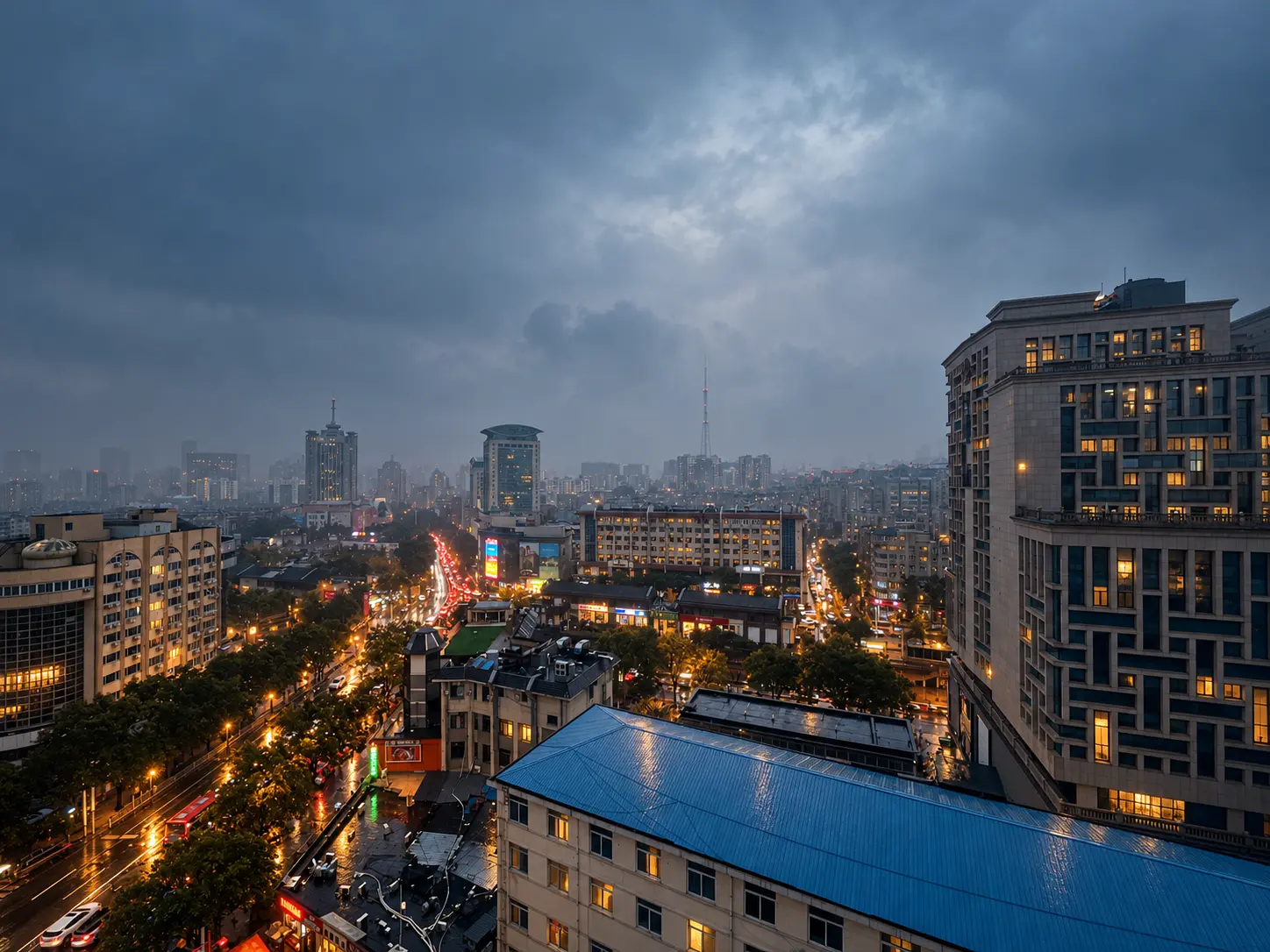 阴雨天色下的城市全景,街上的车灯与楼宇窗口透出暖光